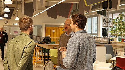 Impression des Workshops: Zwei Mitarbeiter unterhalten sich mit einem Teilnehmer.